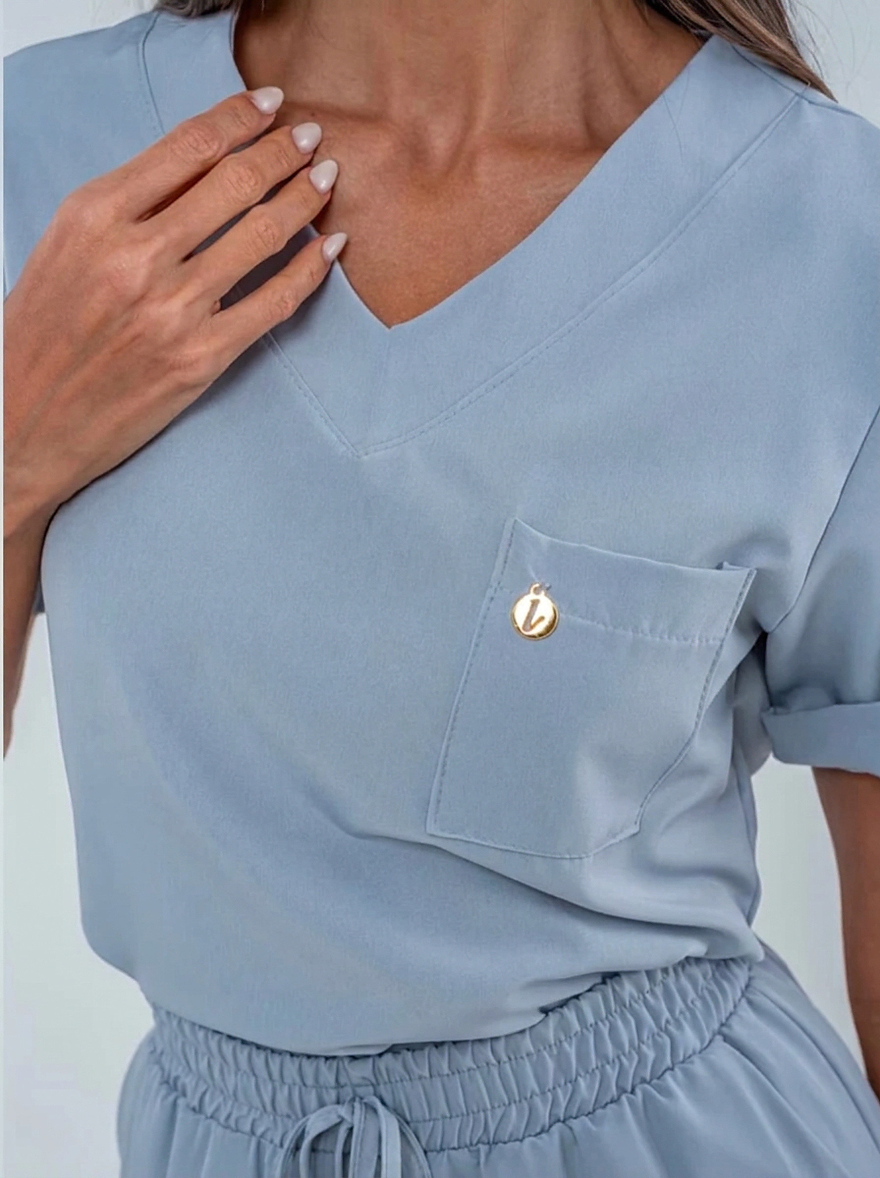 Detalhe do decote e bolso com monograma dourado Madame Scrub